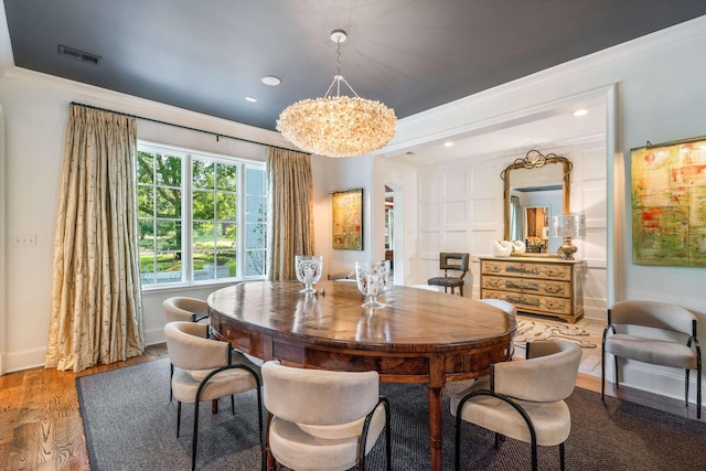 dining space featuring hardwood / wood-style flooring, ornamental molding, and an inviting chandelier