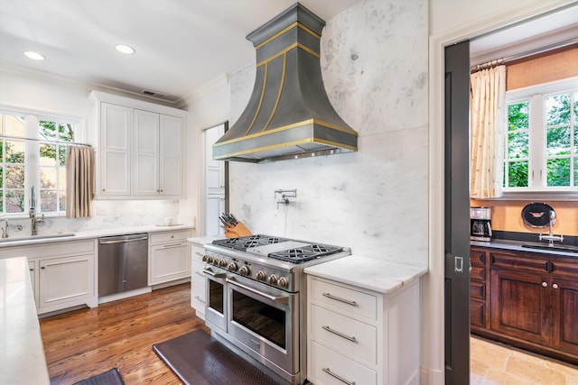 kitchen featuring sink, white cabinetry, premium range hood, and stainless steel appliances