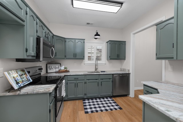 kitchen featuring appliances with stainless steel finishes, light wood-type flooring, a textured ceiling, and sink