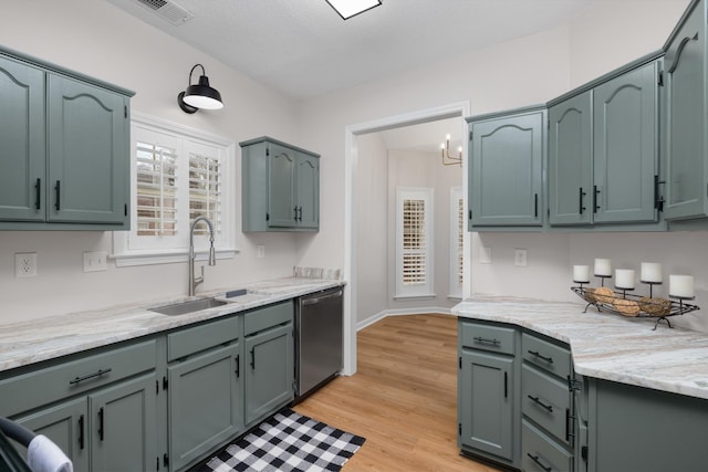 kitchen featuring dishwasher, sink, light hardwood / wood-style flooring, a textured ceiling, and a notable chandelier