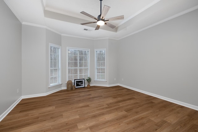 spare room with a tray ceiling, hardwood / wood-style flooring, crown molding, and ceiling fan