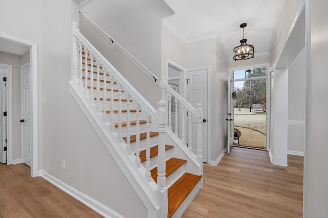 entryway featuring light wood-type flooring, crown molding, and a notable chandelier