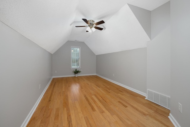 bonus room with a textured ceiling, ceiling fan, lofted ceiling, and light wood-type flooring