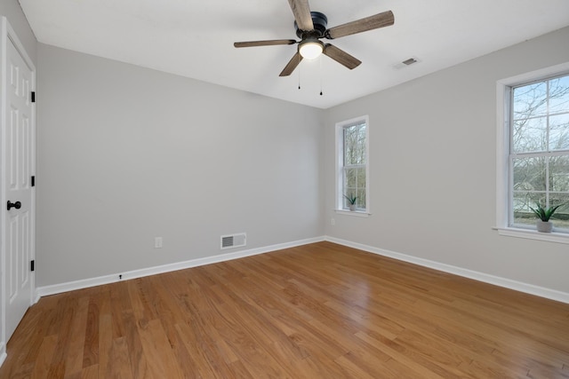 empty room with a healthy amount of sunlight, ceiling fan, and light hardwood / wood-style floors