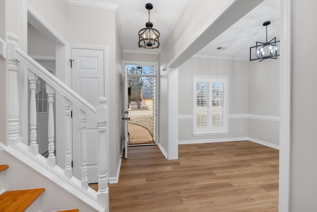 entryway with crown molding, hardwood / wood-style floors, and a chandelier