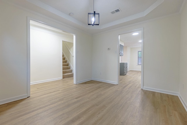 unfurnished dining area featuring a tray ceiling, crown molding, and light hardwood / wood-style floors