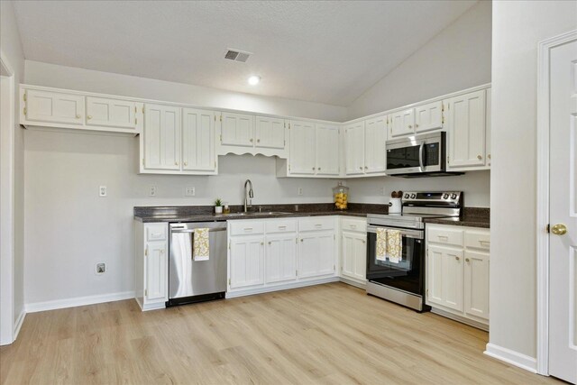 kitchen with sink, white cabinets, light hardwood / wood-style flooring, and appliances with stainless steel finishes