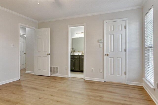 unfurnished bedroom featuring ensuite bathroom, light wood-type flooring, ornamental molding, and multiple windows