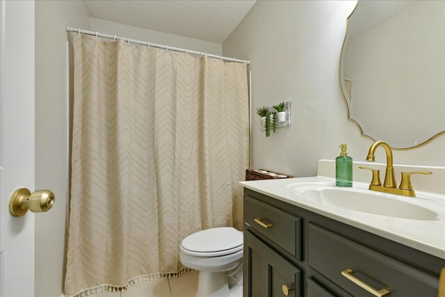 bathroom featuring tile patterned floors, vanity, toilet, and a textured ceiling