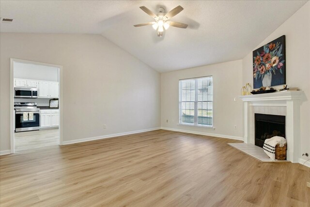 unfurnished living room with ceiling fan, light wood-type flooring, a fireplace, and vaulted ceiling