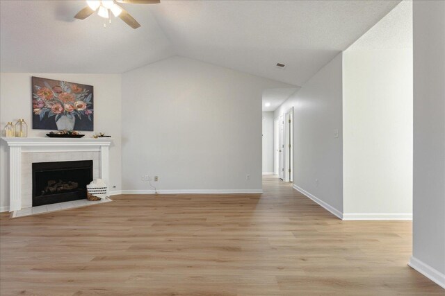 unfurnished living room with lofted ceiling, ceiling fan, light wood-type flooring, and a fireplace