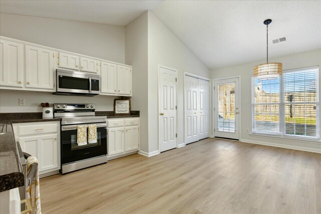 kitchen with lofted ceiling, white cabinetry, stainless steel appliances, and hanging light fixtures