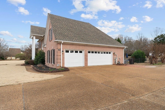 view of side of home featuring brick siding, driveway, and roof with shingles