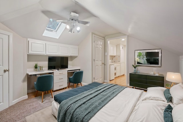 carpeted bedroom with ensuite bath, ceiling fan, and lofted ceiling with skylight