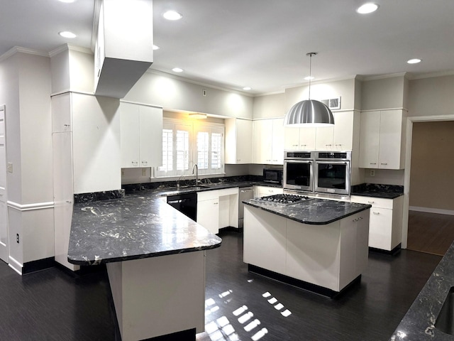 kitchen featuring appliances with stainless steel finishes, decorative light fixtures, a kitchen island, white cabinetry, and a breakfast bar area