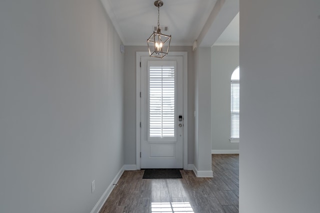 entryway featuring a notable chandelier, dark hardwood / wood-style floors, and ornamental molding