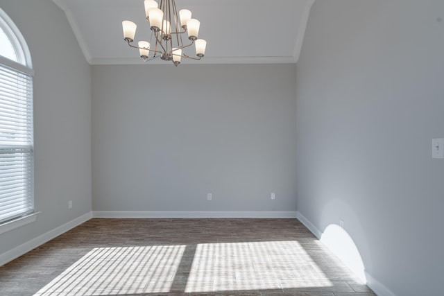 spare room with hardwood / wood-style flooring, lofted ceiling, ornamental molding, and an inviting chandelier