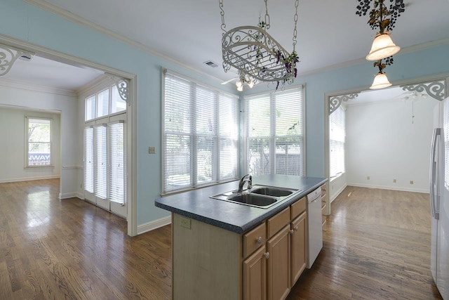 kitchen featuring white dishwasher, a healthy amount of sunlight, sink, decorative light fixtures, and a center island with sink