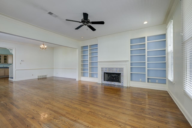 unfurnished living room featuring crown molding, built in features, wood-type flooring, and ceiling fan with notable chandelier