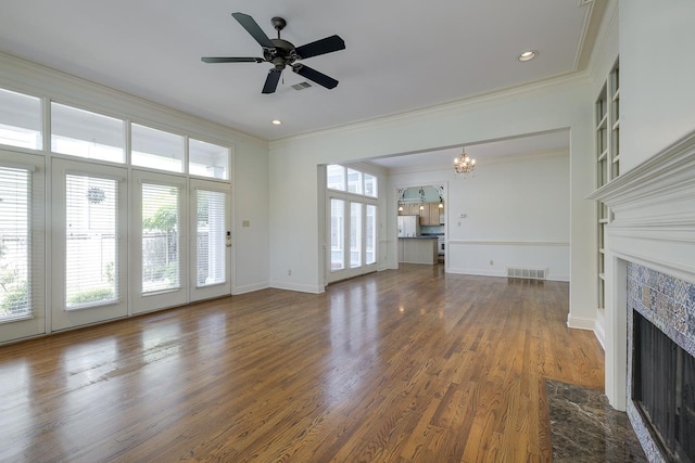 unfurnished living room featuring ceiling fan with notable chandelier, dark hardwood / wood-style floors, a premium fireplace, and ornamental molding