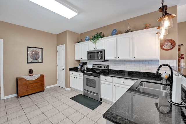 kitchen featuring sink, hanging light fixtures, stainless steel appliances, dark stone countertops, and white cabinets