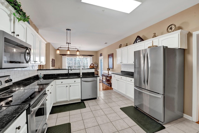 kitchen featuring white cabinetry, sink, decorative light fixtures, decorative backsplash, and appliances with stainless steel finishes