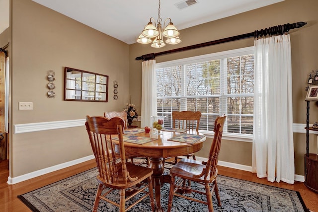 dining area featuring wood-type flooring and an inviting chandelier