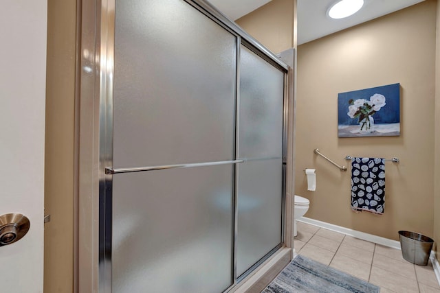 bathroom featuring tile patterned flooring, a shower with shower door, and toilet