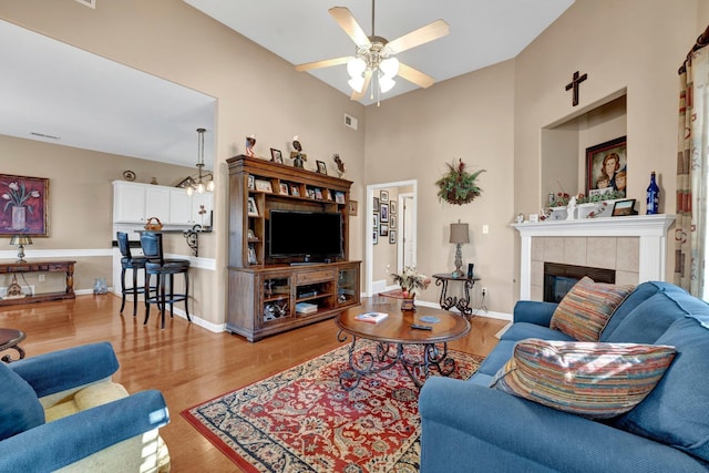 living room with a fireplace, light wood-type flooring, and ceiling fan