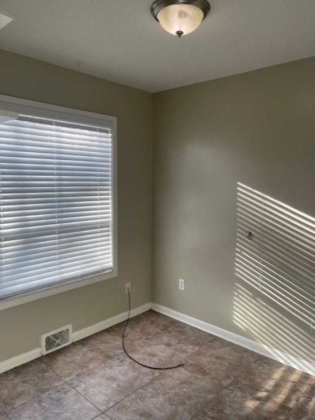 empty room with tile patterned flooring and plenty of natural light