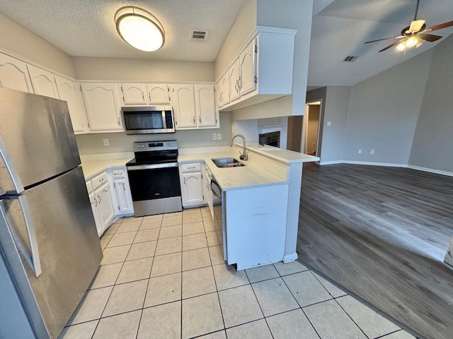 kitchen with white cabinets, sink, kitchen peninsula, and stainless steel appliances