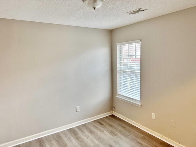 spare room featuring a textured ceiling and light hardwood / wood-style flooring