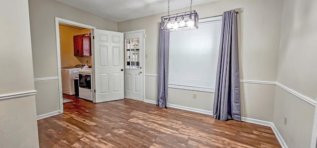 unfurnished dining area featuring independent washer and dryer, dark hardwood / wood-style flooring, and a textured ceiling