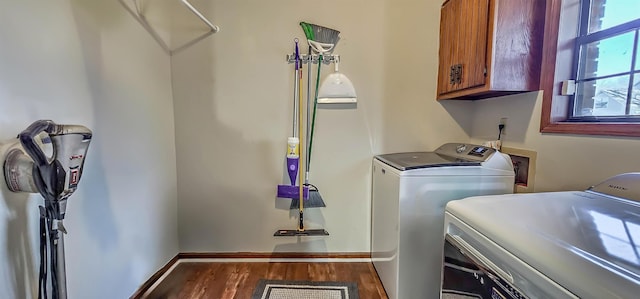 laundry area with washing machine and clothes dryer, dark wood-type flooring, and cabinets