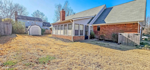 rear view of house featuring a shed, a lawn, and a sunroom