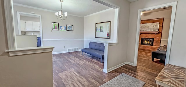 living area featuring dark hardwood / wood-style floors, ornamental molding, a fireplace, and an inviting chandelier