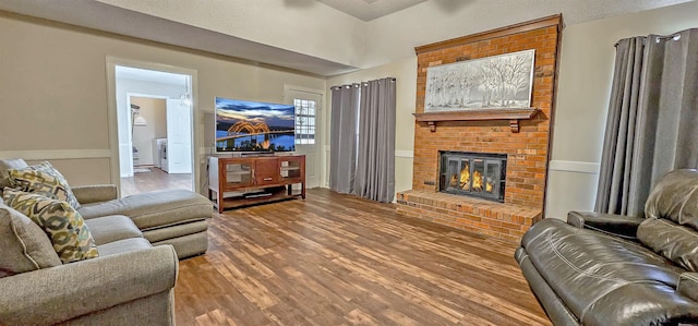 living room featuring hardwood / wood-style floors, a textured ceiling, and a brick fireplace