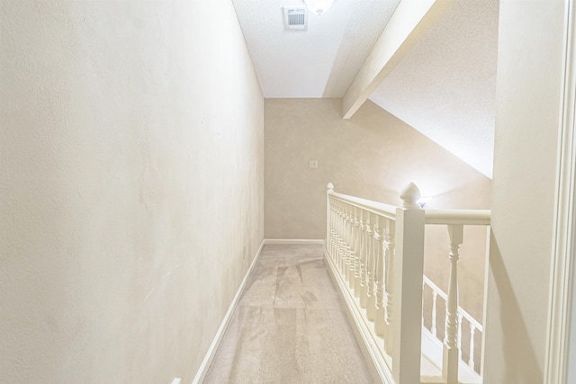 hallway featuring carpet, lofted ceiling with beams, and a textured ceiling