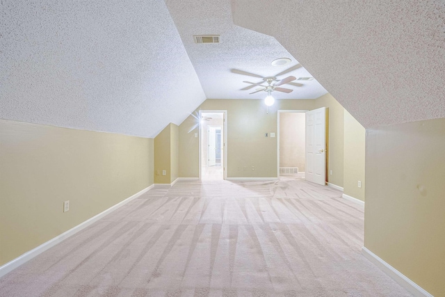 additional living space featuring light carpet, a textured ceiling, ceiling fan, and lofted ceiling