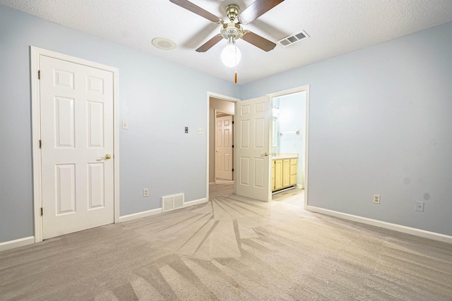 unfurnished bedroom featuring connected bathroom, ceiling fan, light carpet, and a textured ceiling