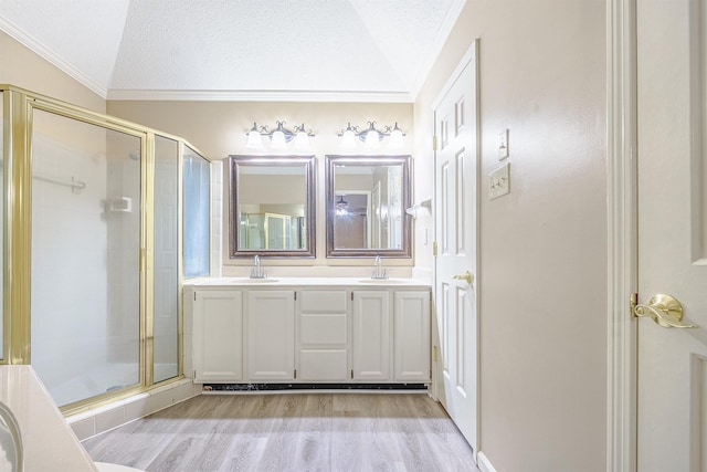 bathroom featuring walk in shower, wood-type flooring, a textured ceiling, vaulted ceiling, and vanity