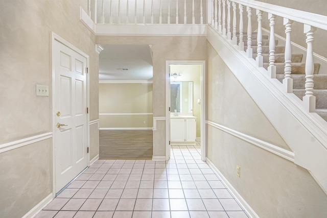 tiled entryway with ornamental molding and sink