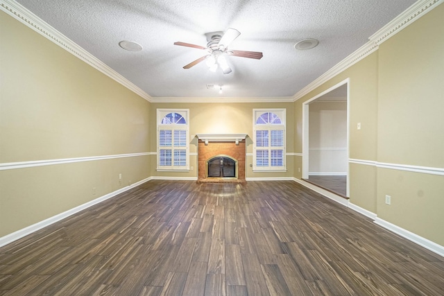 unfurnished living room featuring a brick fireplace, a textured ceiling, ceiling fan, crown molding, and dark hardwood / wood-style floors