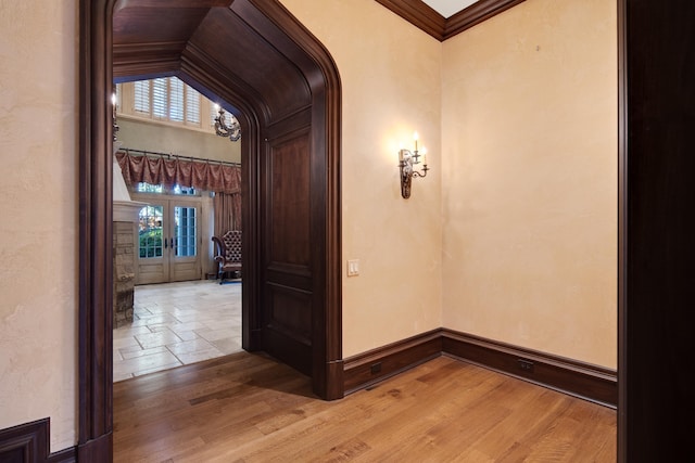 hallway with light wood-type flooring, a wealth of natural light, and french doors