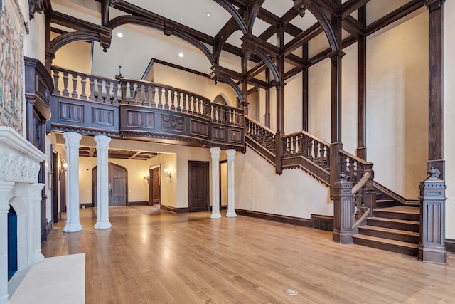 living room with ornate columns, coffered ceiling, a towering ceiling, hardwood / wood-style flooring, and ornamental molding