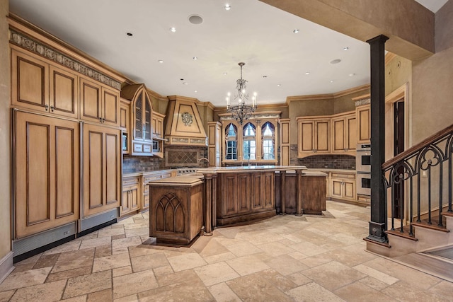 kitchen with a center island, backsplash, hanging light fixtures, double oven, and a notable chandelier