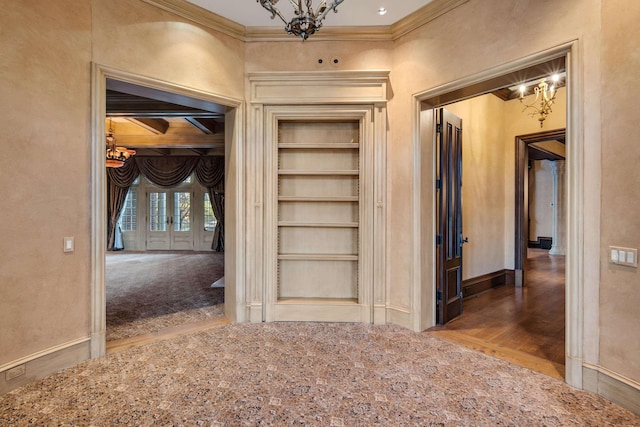 hallway featuring built in shelves, ornamental molding, and an inviting chandelier