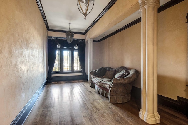 sitting room featuring wood-type flooring, ornate columns, and ornamental molding