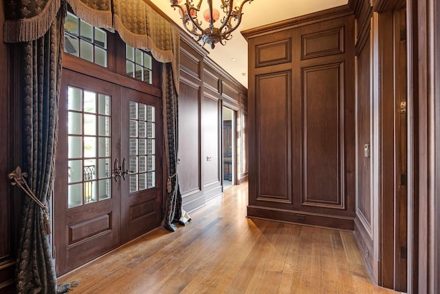 interior space with light hardwood / wood-style flooring, french doors, and a notable chandelier