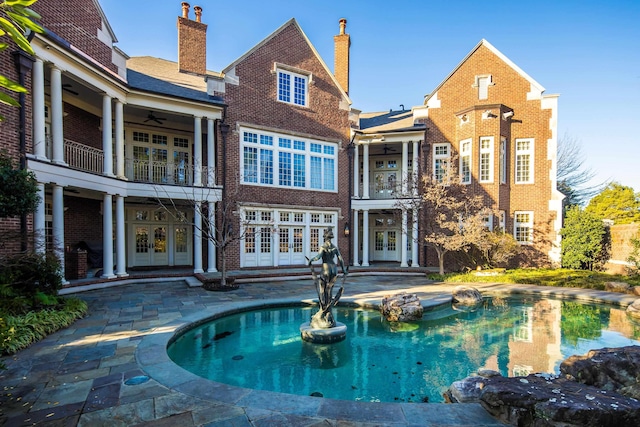 back of house with ceiling fan, a patio area, a balcony, and french doors